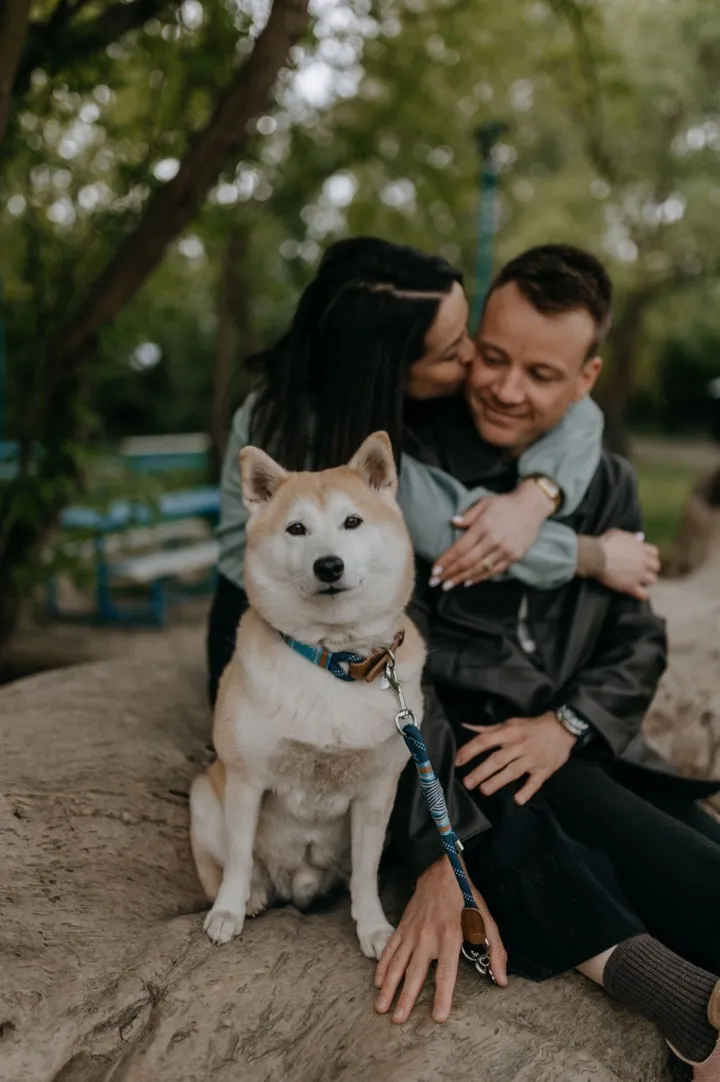 Góré, a shiba inu ül a kép előterében, mögötte Anna és Peti egymást átölelve